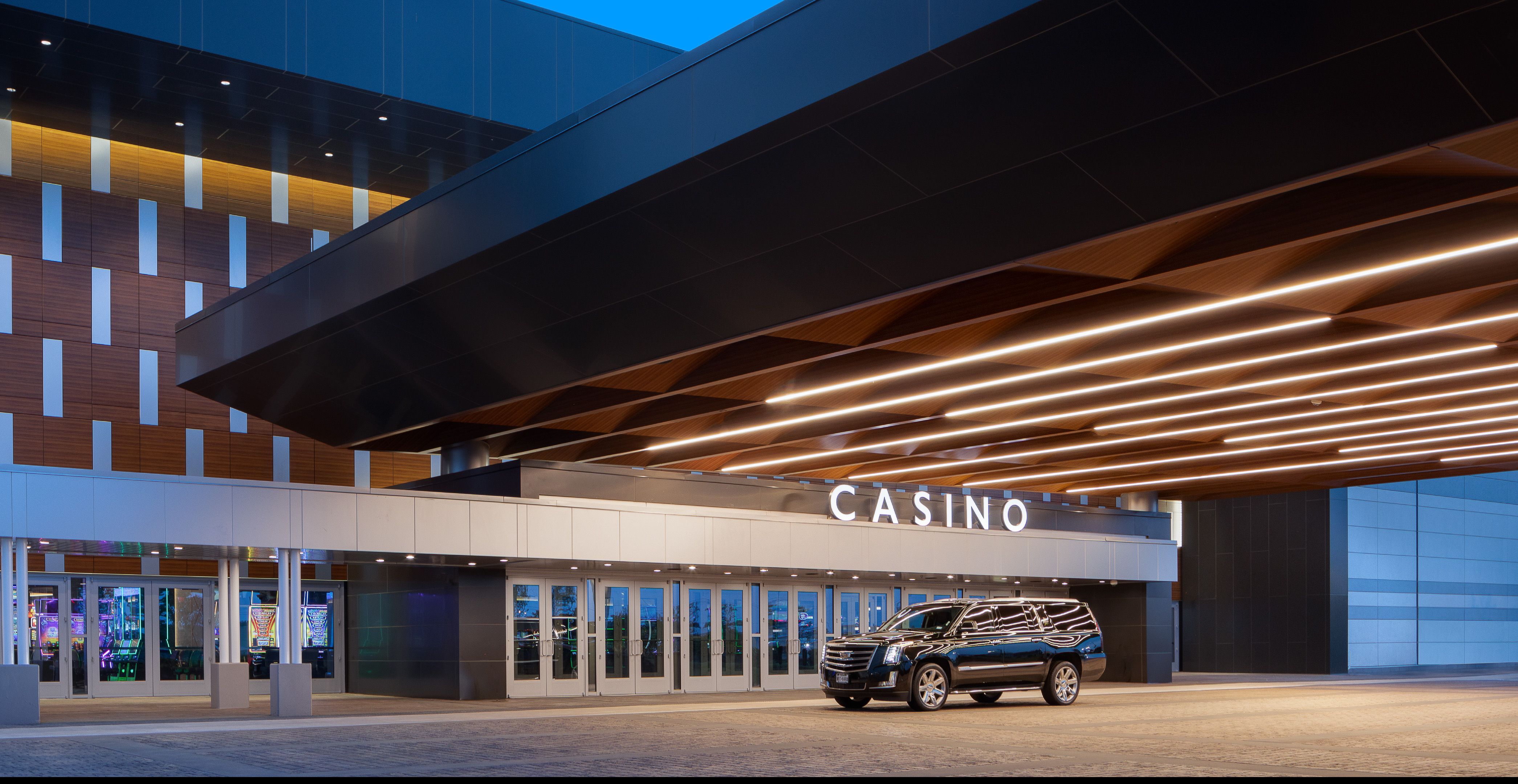 A Cadillac SUV is parked in front of some doors. Above it is the word 'Casino' and some diagonal light fixtures